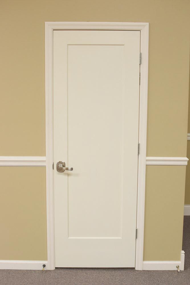 White door with silver handle centered in a tan wall with white molding.
