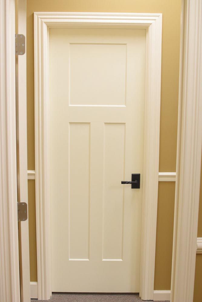 Closed white interior door with black handle and decorative molding.