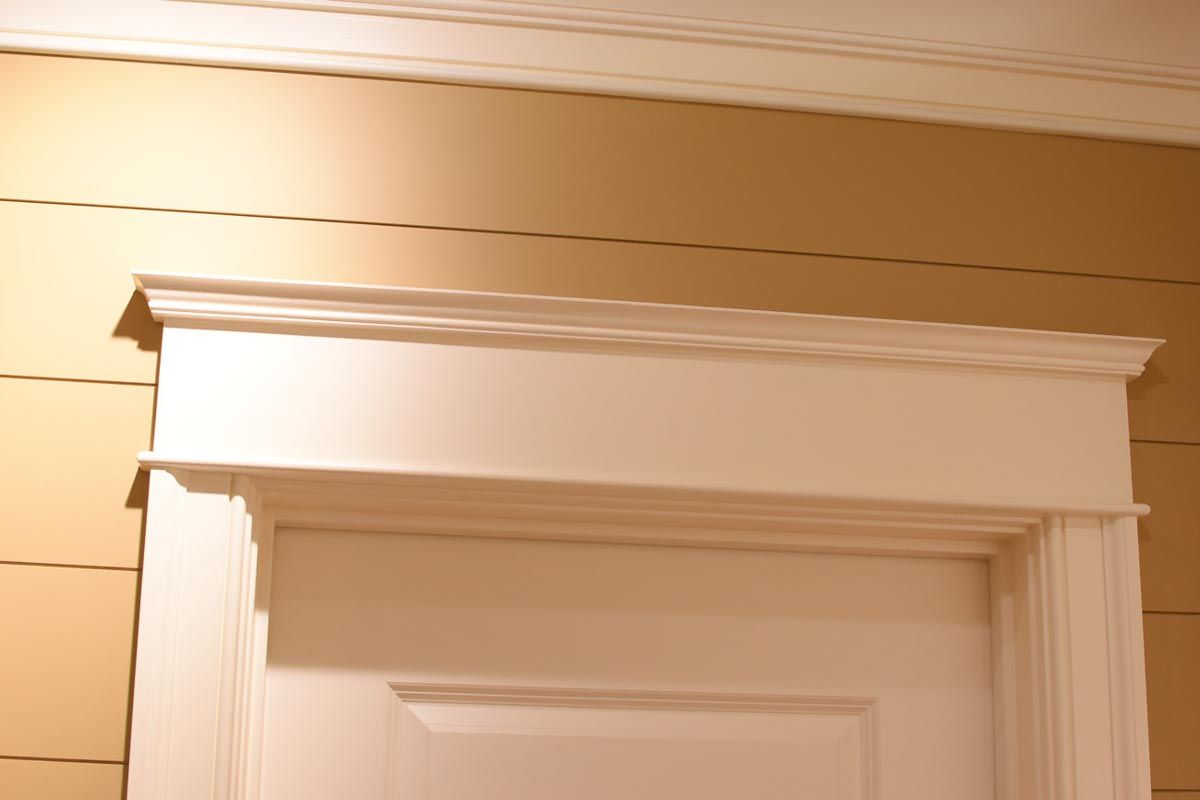 White door frame with decorative crown molding against a light yellow wall.
