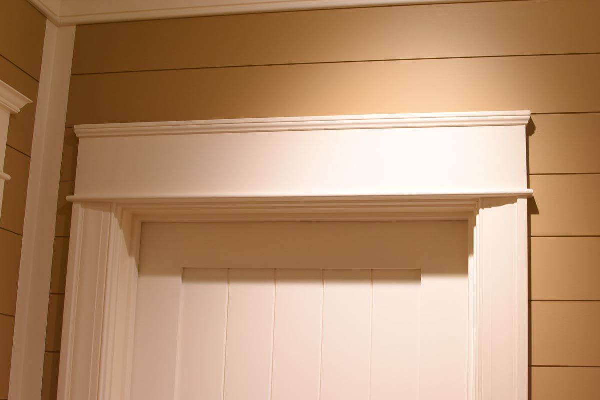 White doorframe with detailed molding and a decorative shelf against a tan wall.