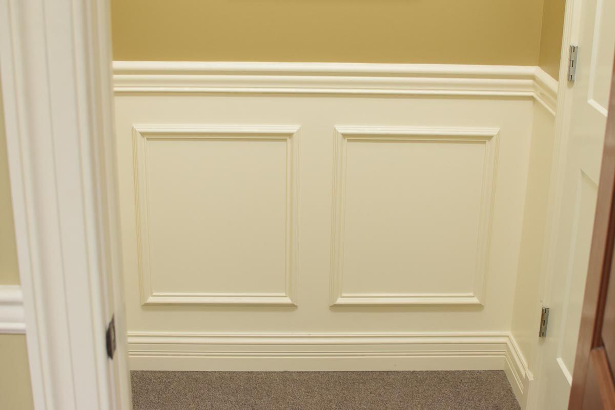 Cream-colored wainscoting with two square panels in a small room, between door frames.