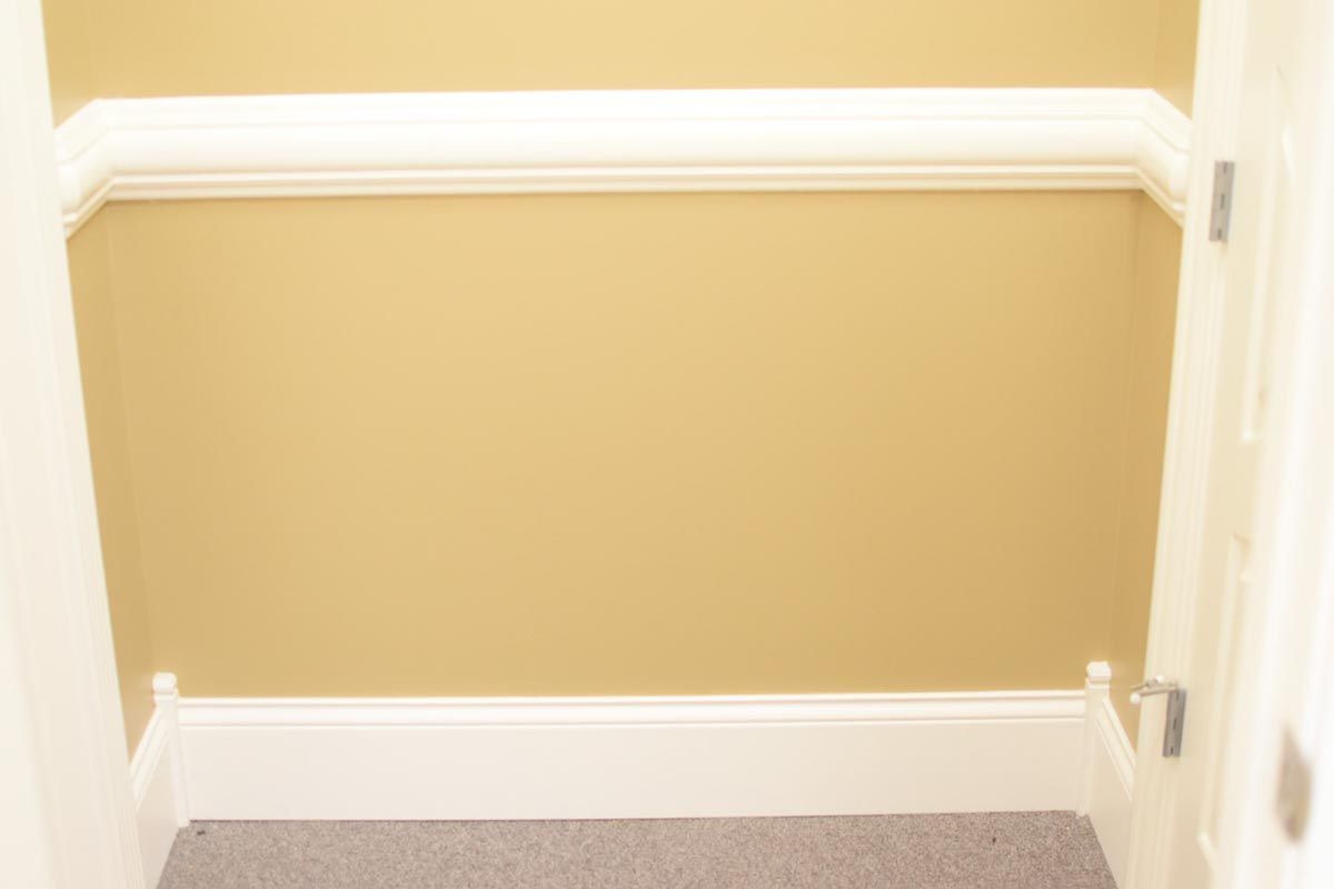 Empty closet with cream trim and gold walls.