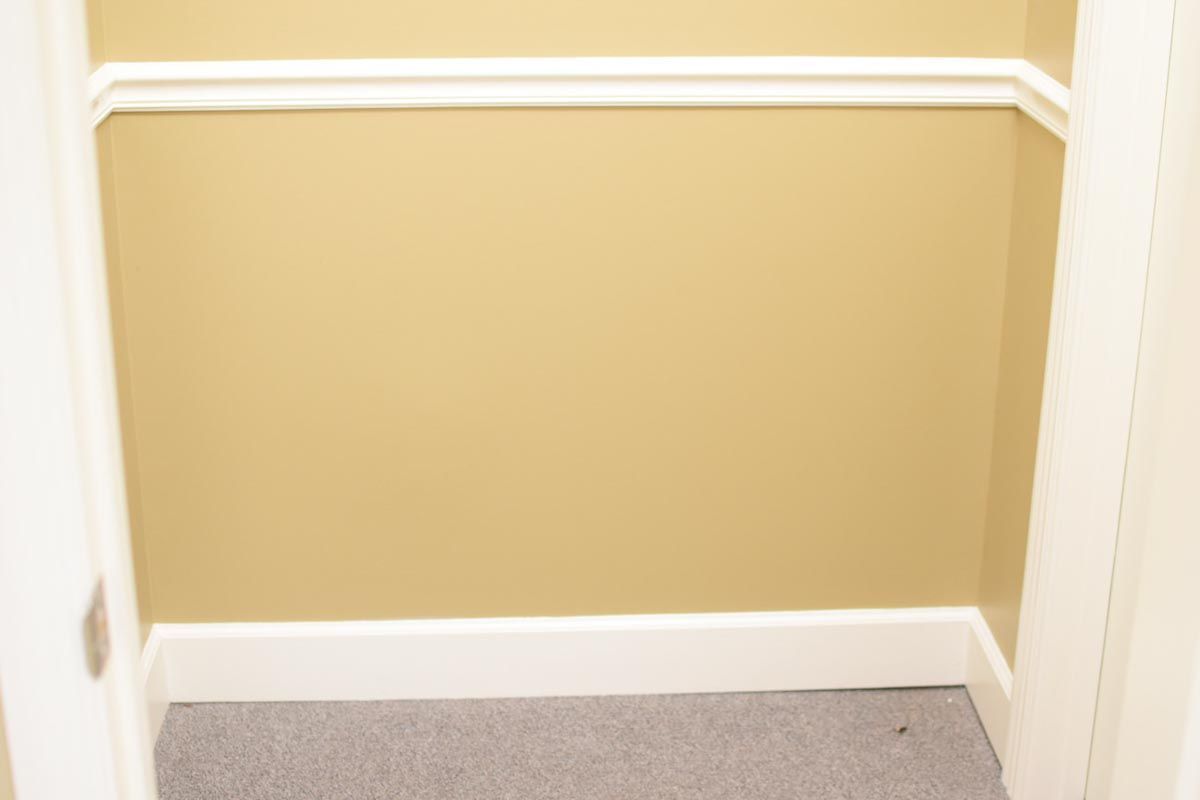 Empty closet with tan walls, white trim, and gray carpet.
