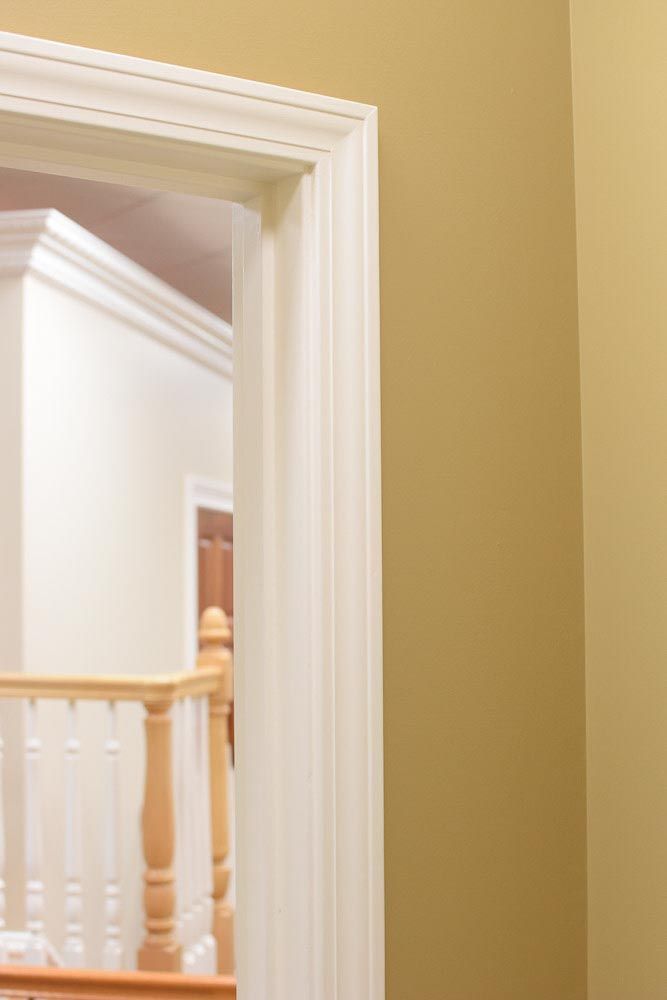 White door frame with a glimpse of a hallway. Yellow walls.