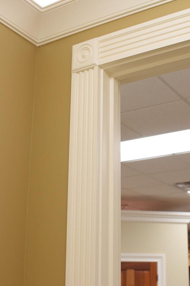 Cream-colored architectural doorway with fluted columns and decorative molding; gold wall in the corner.