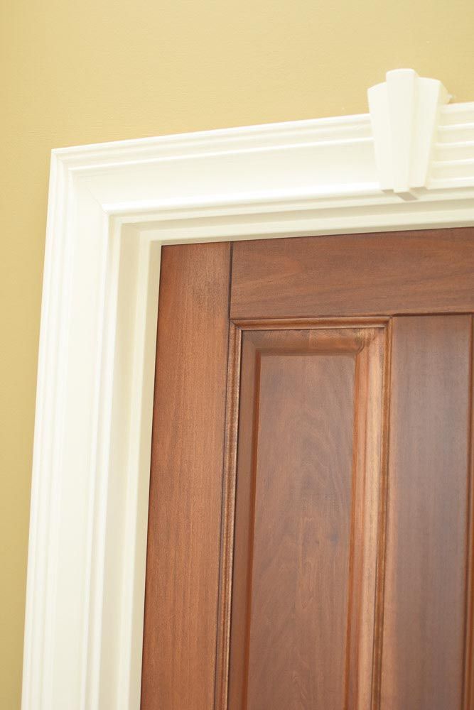 Wooden door with white trim and decorative crown molding.