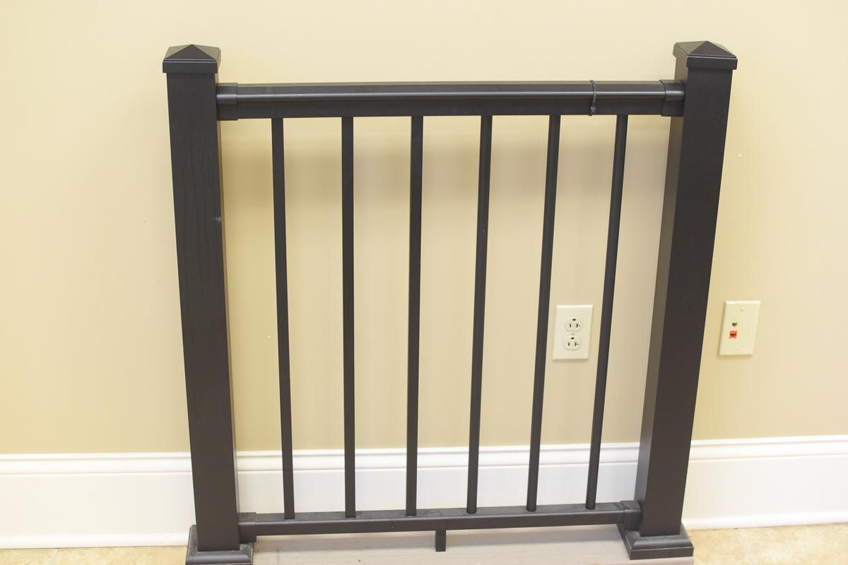 Black metal railing against a beige wall with a white baseboard and outlet.