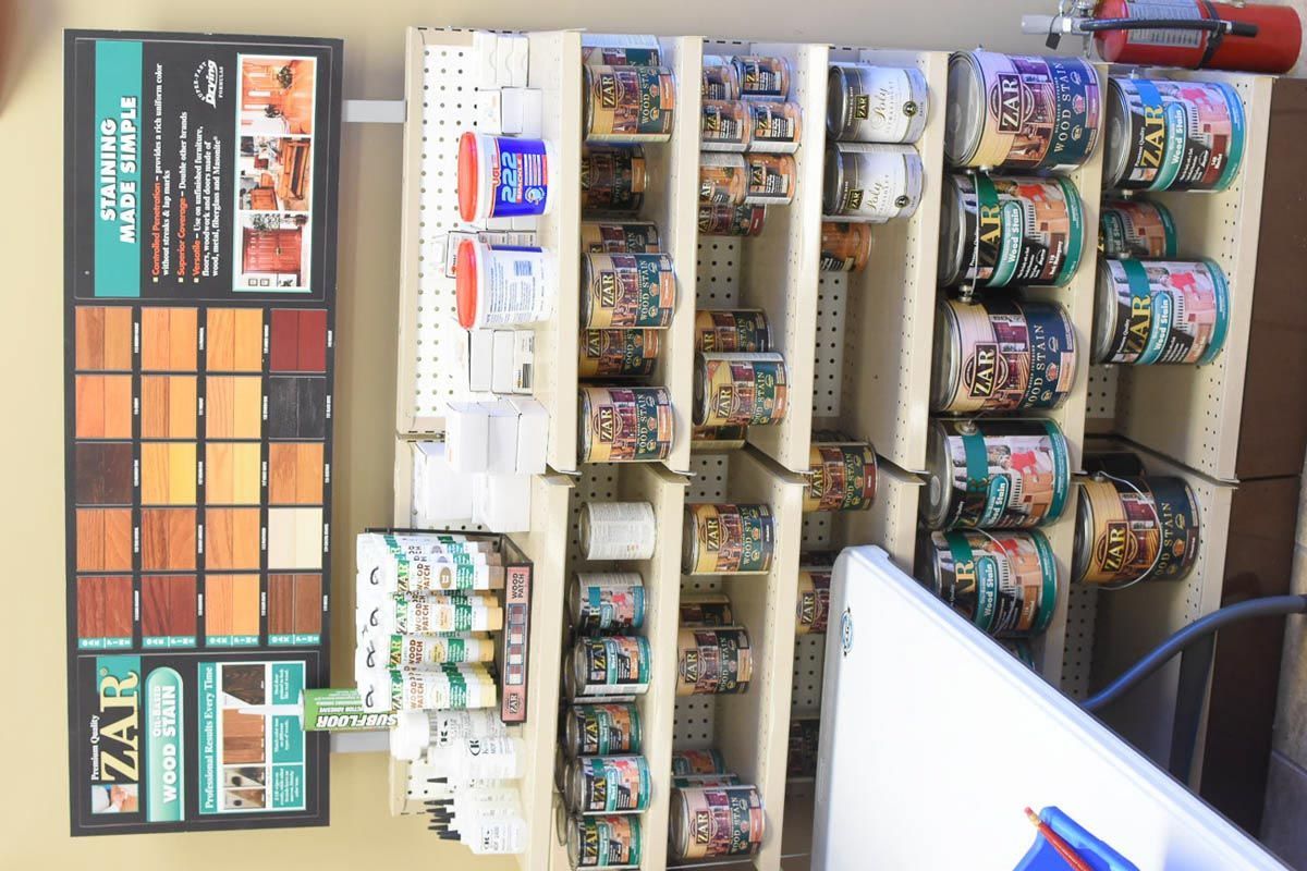 Paint and stain display at a hardware store. Various cans and color samples on shelves.