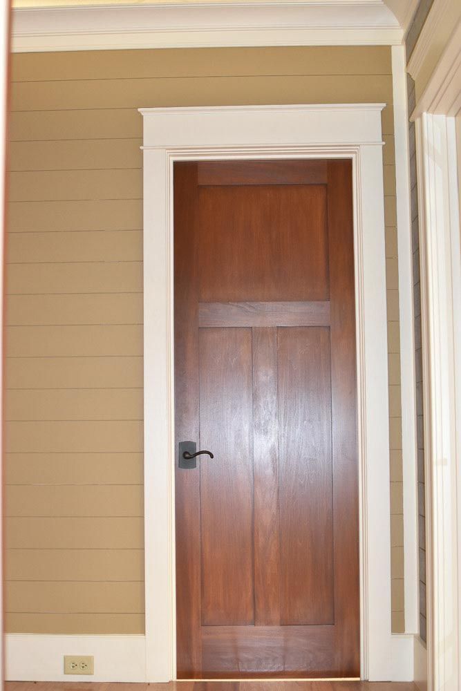 Wooden door with white trim set in tan wall.
