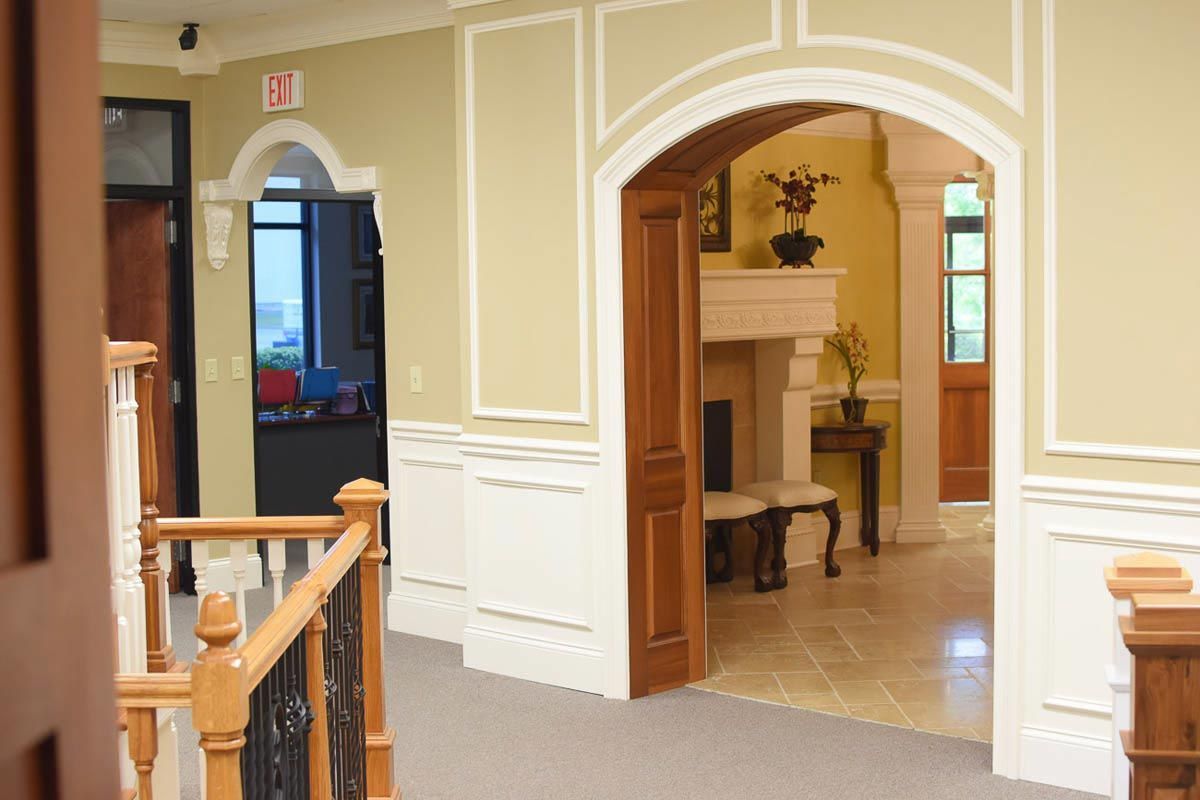 Hallway with archways, doors, and a fireplace. Beige walls, wood trim, and a staircase visible.