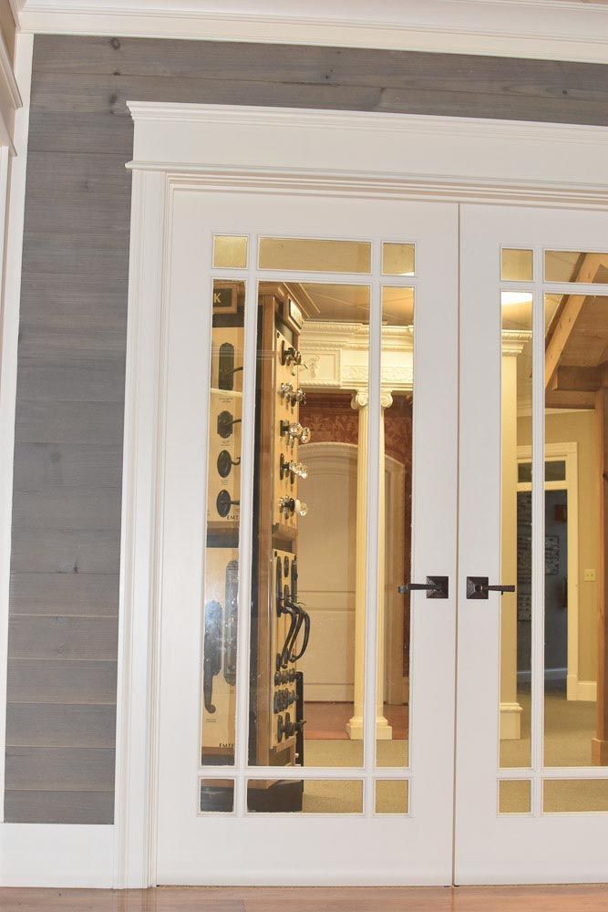 White French doors with glass panes, black handles, and elaborate trim. View of interior.