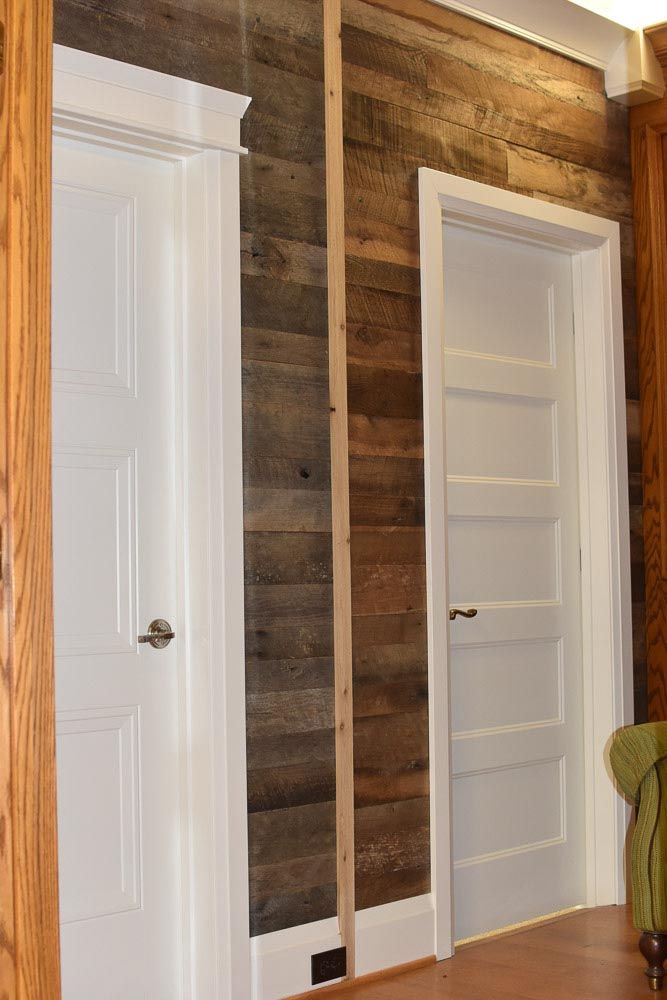 Wood plank wall between two white doors; one with a silver handle.