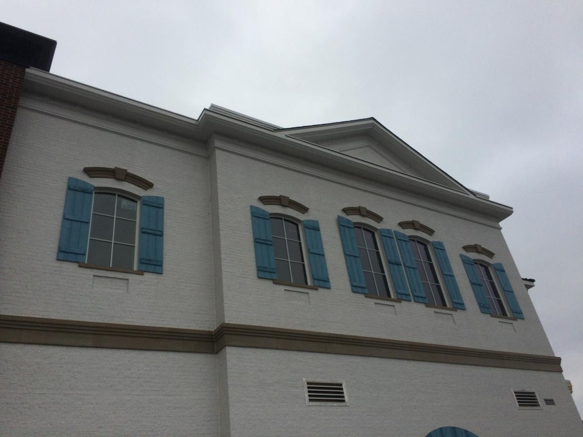 White building with blue shutters against a cloudy sky.