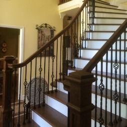 Wooden staircase with dark brown handrail and decorative black spindles.