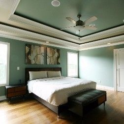 Bedroom with bed, art, windows, green walls and ceiling, hardwood floor, and ceiling fan.