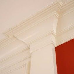 White crown molding and trim on a wall and ceiling; red wall visible.