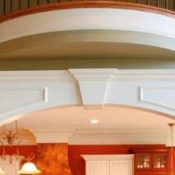 White arched doorway with trim, light fixture, and red wall in background.