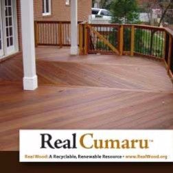Wooden deck made with Cumaru wood, with white pillars and a fence, outside a building.