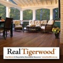 Wooden porch with furniture, surrounded by windows with a forest view.