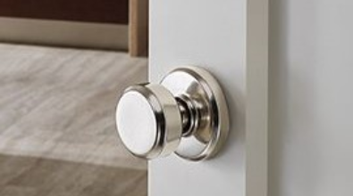 Silver doorknob on a white door. The knob has a round face and circular backplate.