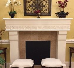 Fireplace with white mantel, artwork, and decor. Two ottomans sit in front.
