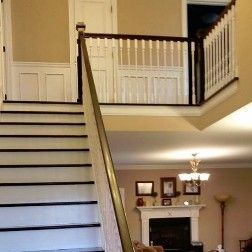 Staircase with white steps, black treads, and a banister leading to an upper level with a railing.