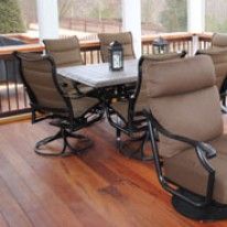 Outdoor dining set on a wooden deck. Table and chairs with brown cushions.