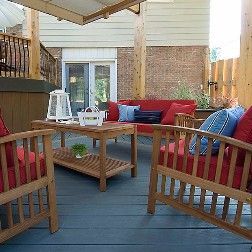 Wooden outdoor patio with furniture and red cushions.