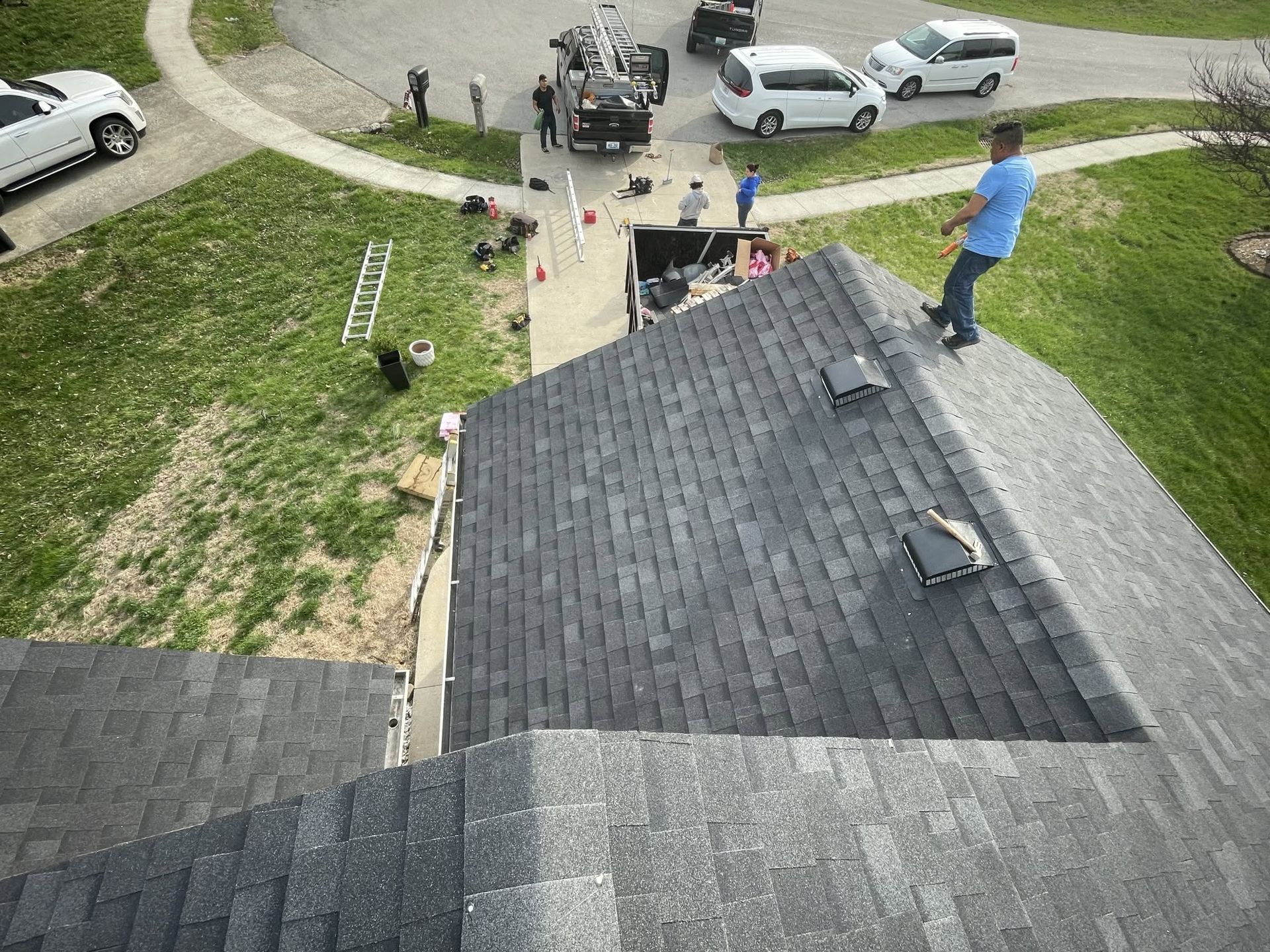 Workers and equipment below a house roof, seen from above after storm damage.