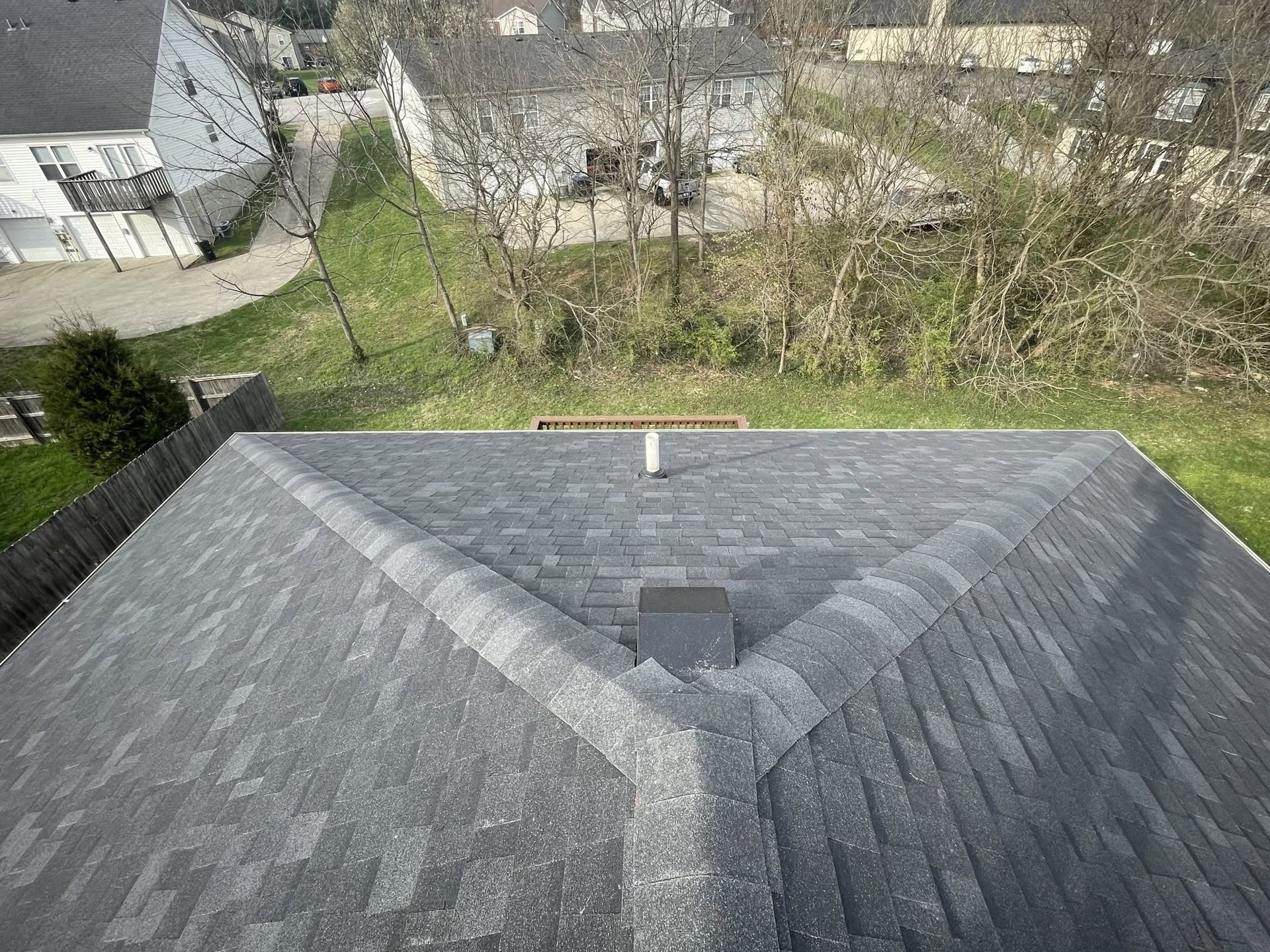 Gray shingled roof with chimney, seen from above in a residential neighborhood