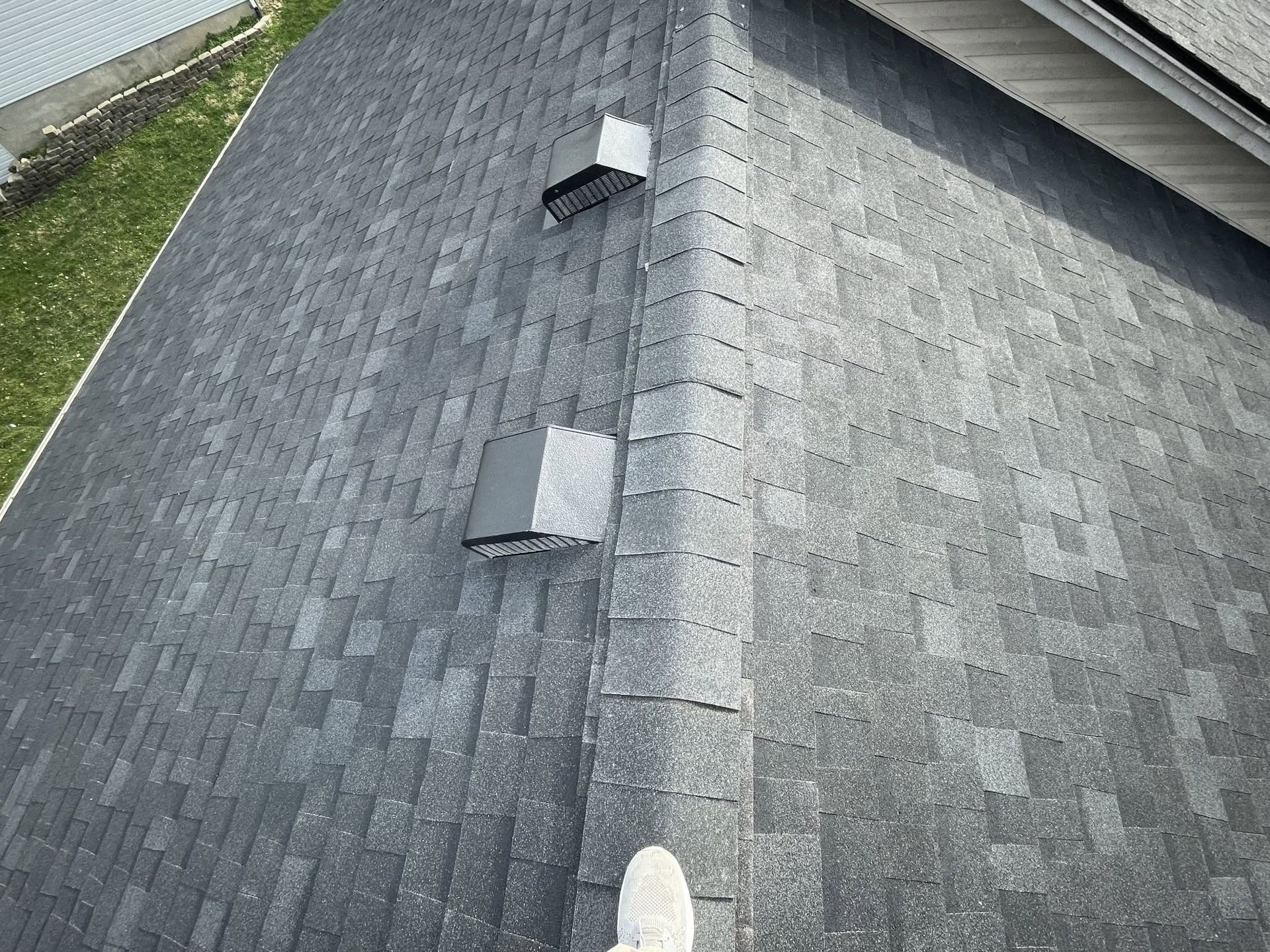 Gray shingled roof with two vents and a ridge line, viewed from above