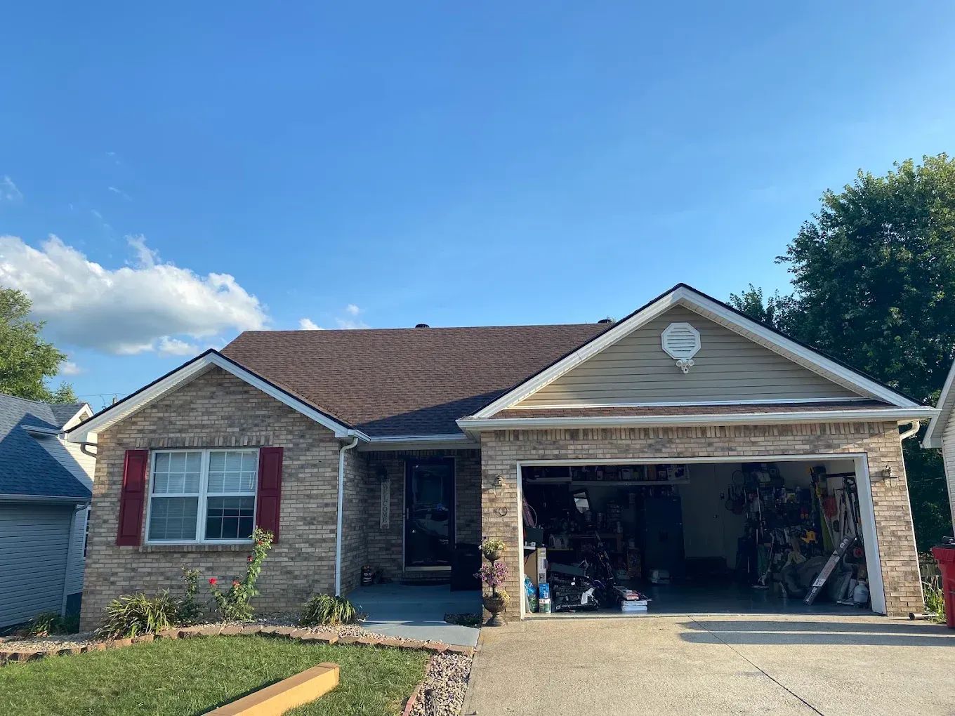 Single-story brick house with an open garage and blue sky on a sunny day