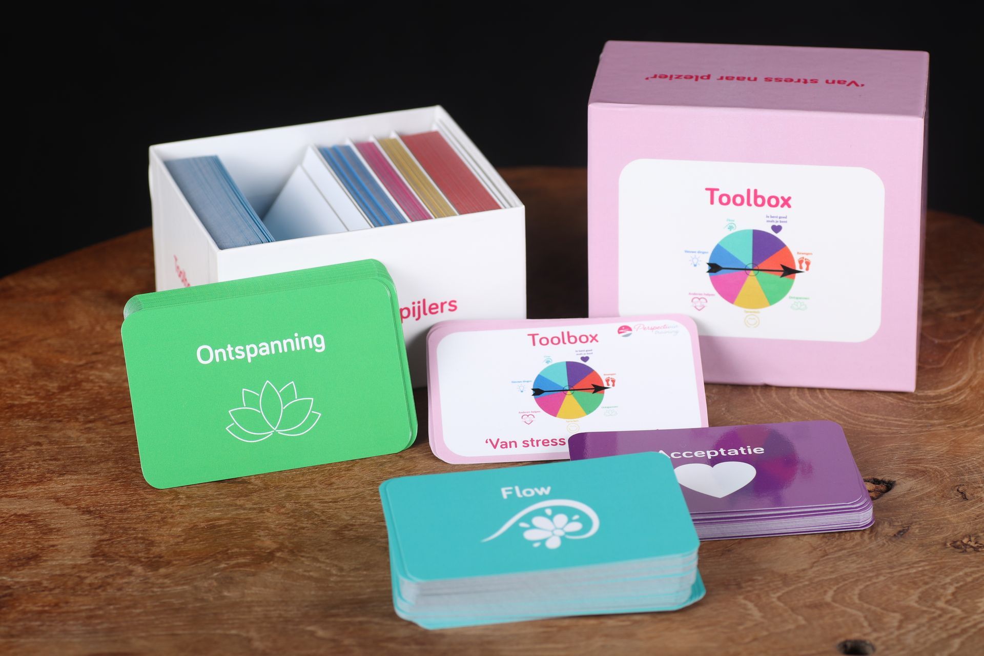 Kleurrijke mindfulness-hulpmiddelen en -kaarten uitgestald op een houten tafel, met daarachter een roze 