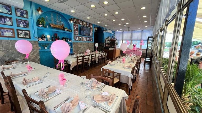 Sala da pranzo del ristorante decorata con palloncini rosa e tavoli apparecchiati per una festa.