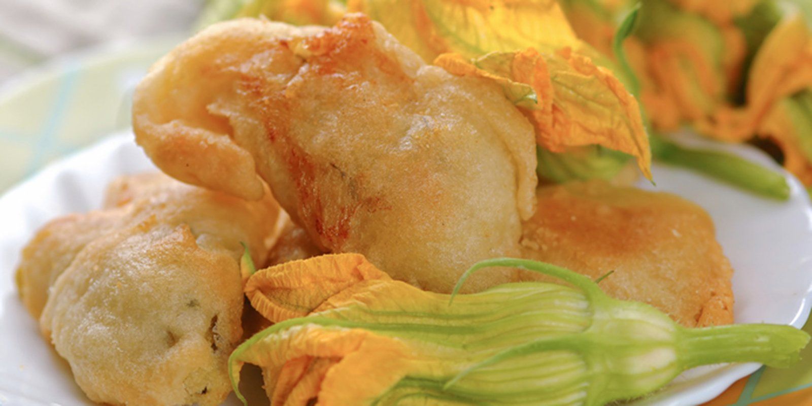 Fiori di zucchina fritti su un piatto, dorati e leggermente impanati