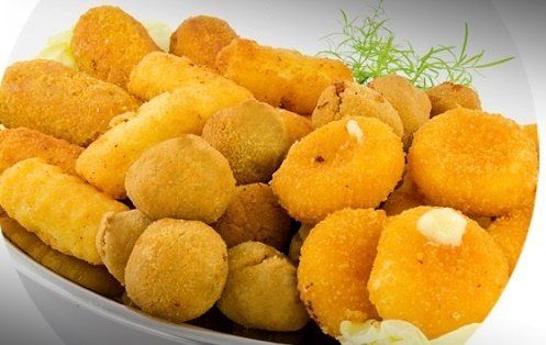 Piatto di snack e crocchette fritti assortiti e dorati su un piatto bianco.