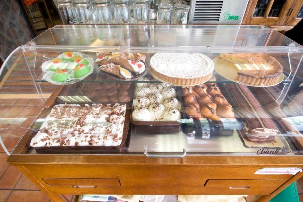Assortimento di pasticcini e dessert esposti in una vetrina da pasticceria.