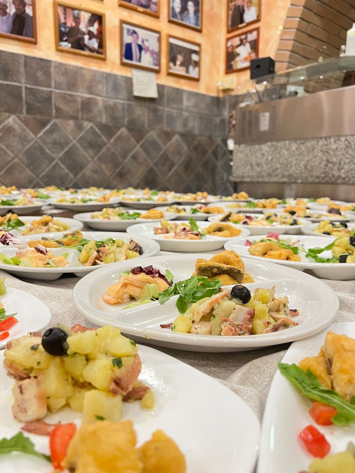 File di antipasti disposti su un tavolo da banchetto in una sala da pranzo piastrellata.