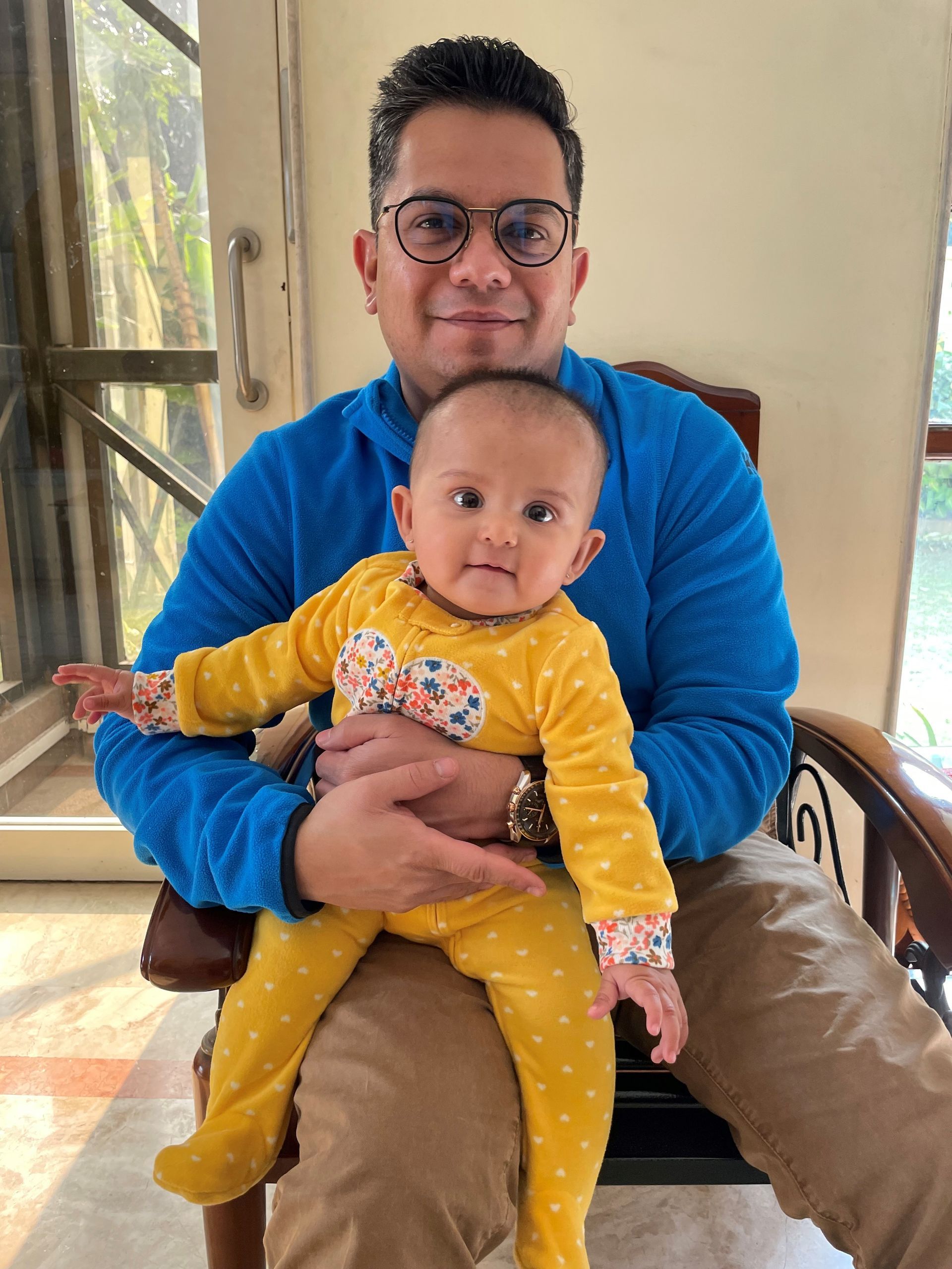 A man is holding a baby in his lap while sitting in a chair.