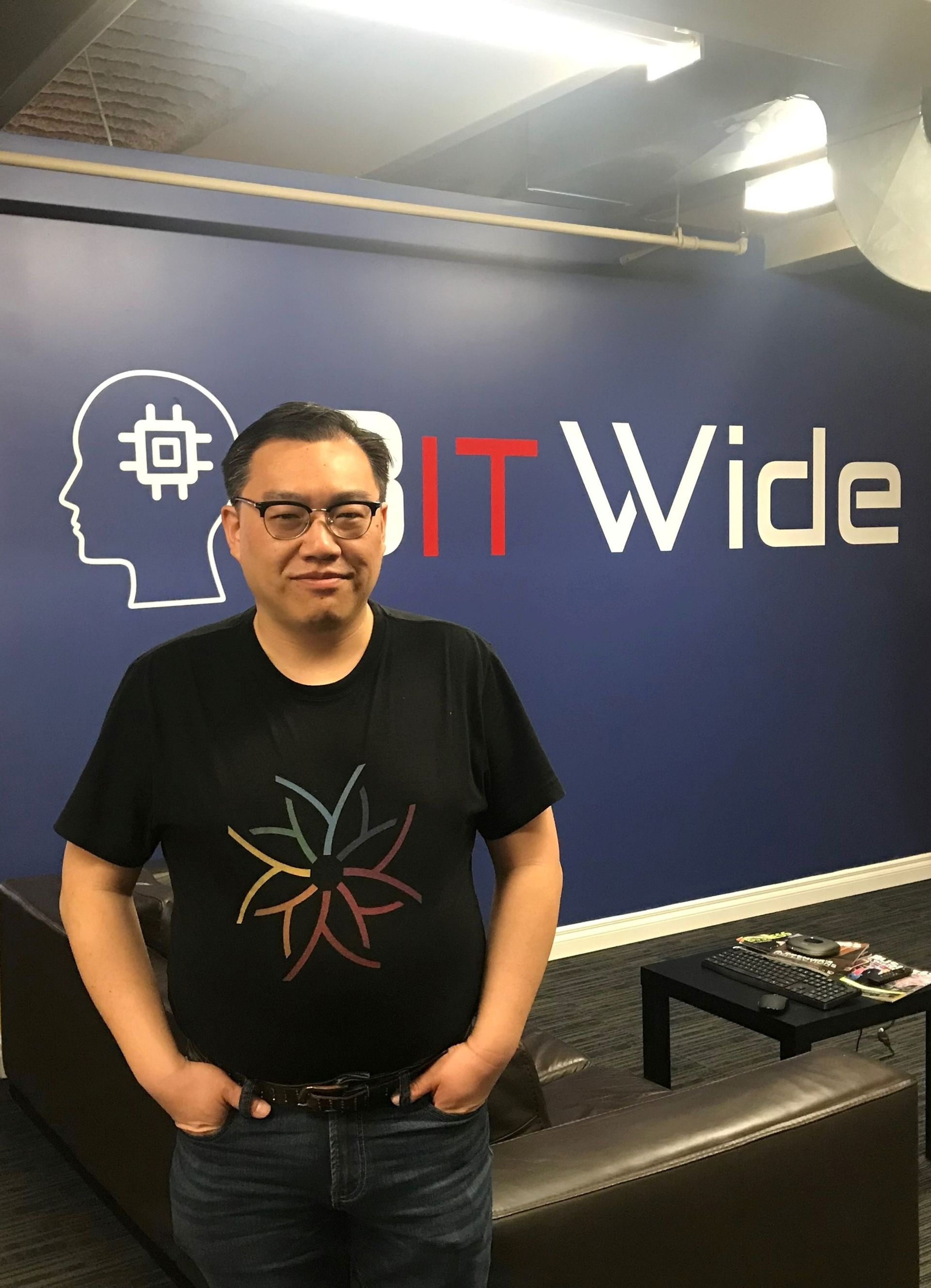 A man standing in front of a wall that says it wide