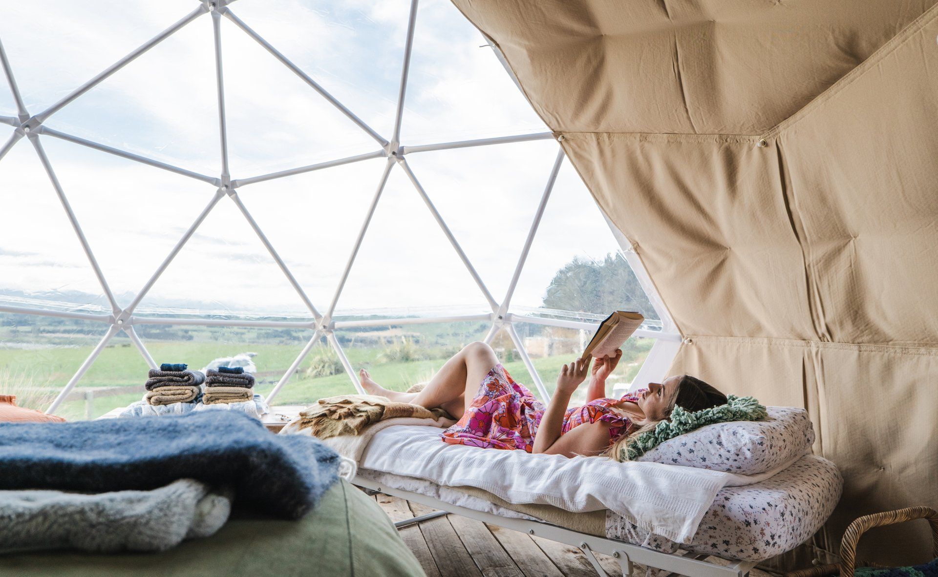 A woman is laying on a bed in a dome reading a book.