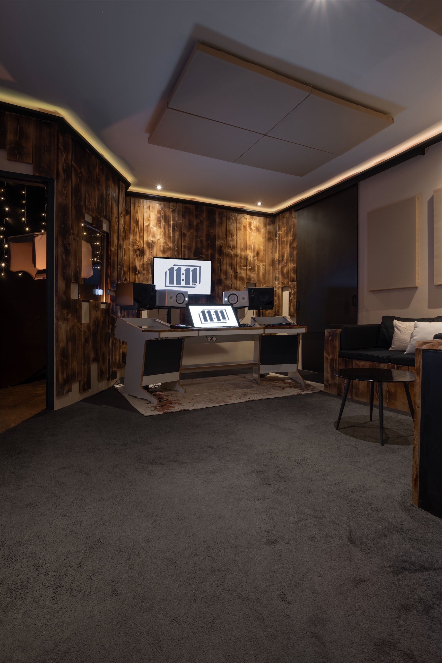 Recording studio with dark wood paneling, a desk with monitors, and a plush carpet.