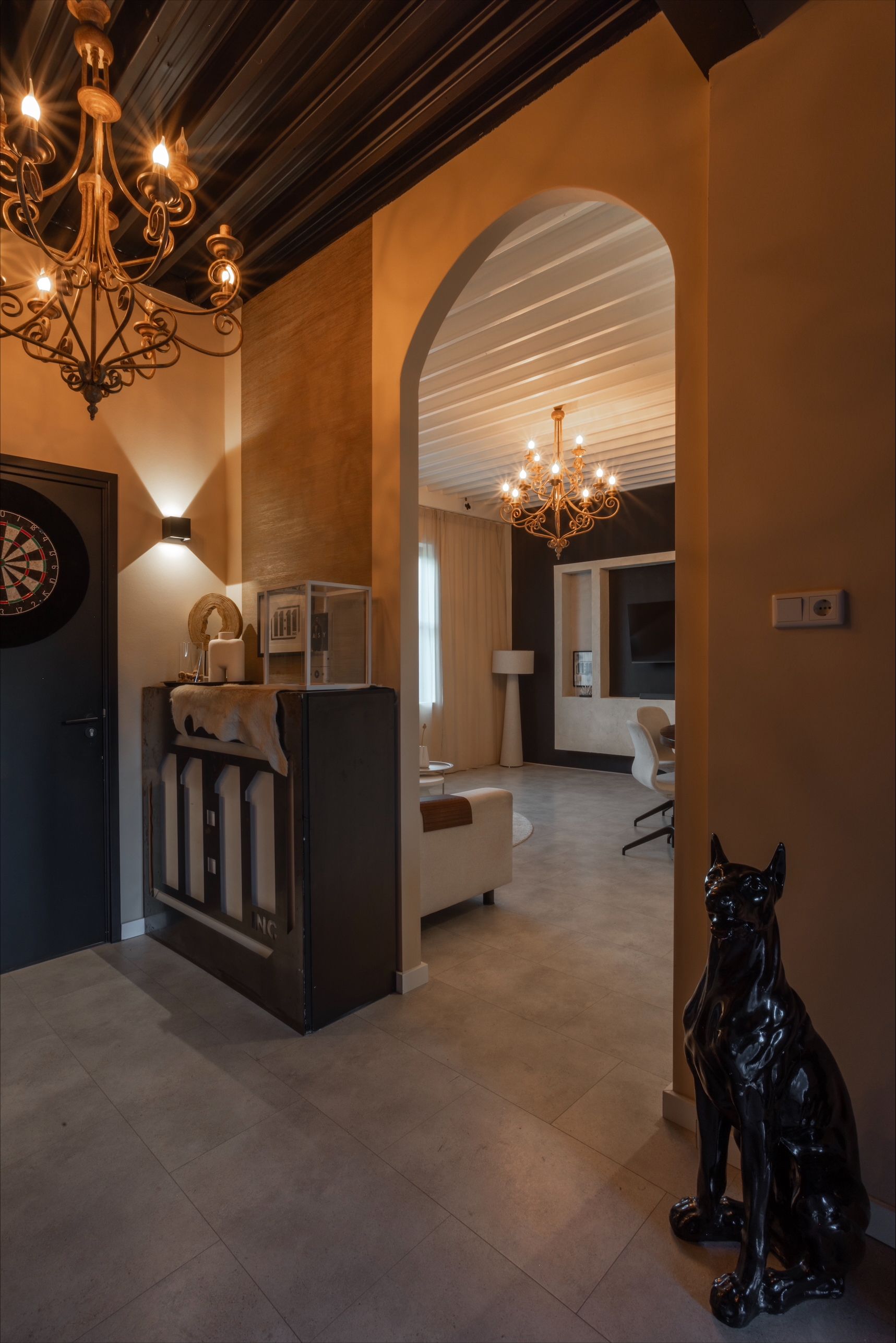 Entryway with a decorative cabinet, archway to a living room, and a black dog statue.
