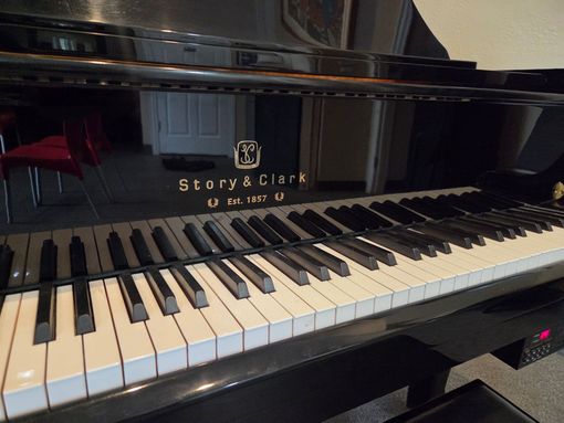 A wooden piano is sitting in front of a white wall.