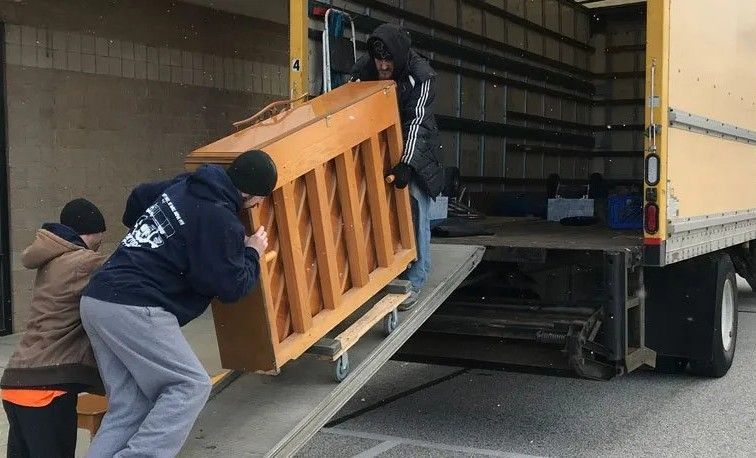 A group of people are loading a piano into a truck.