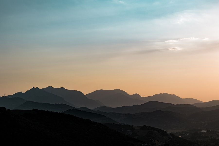 a sunset over a mountain range with a cloudy sky
