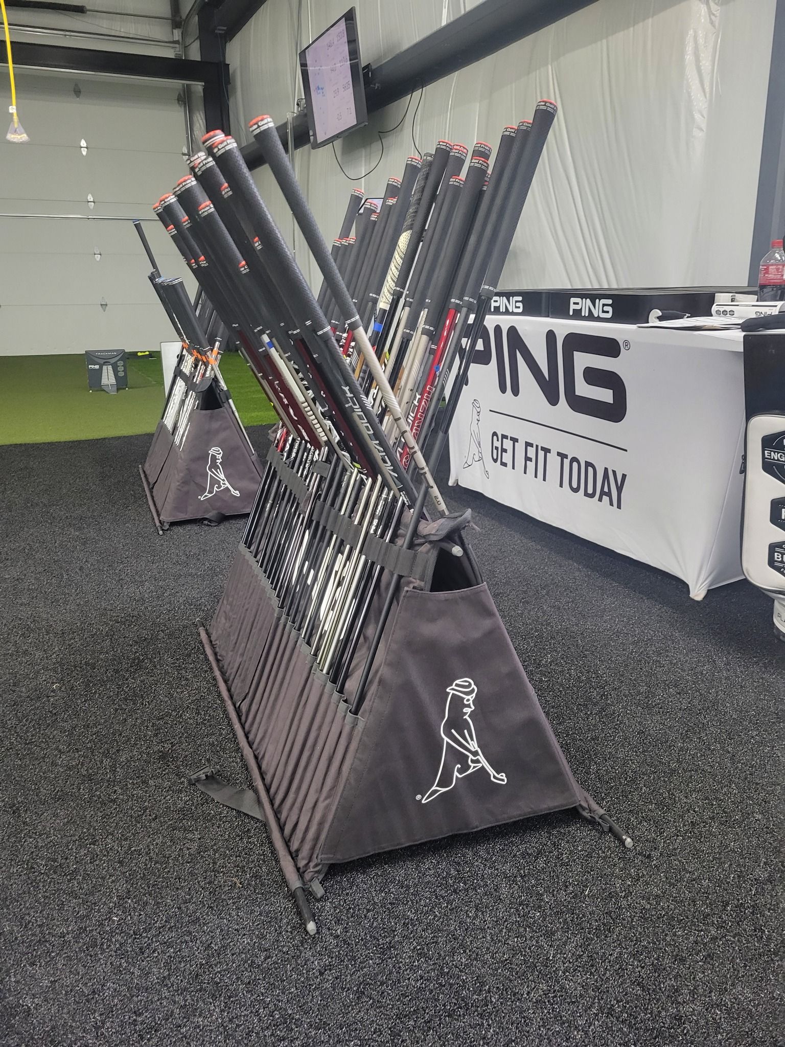 a bunch of golf clubs are sitting in a rack in a room .