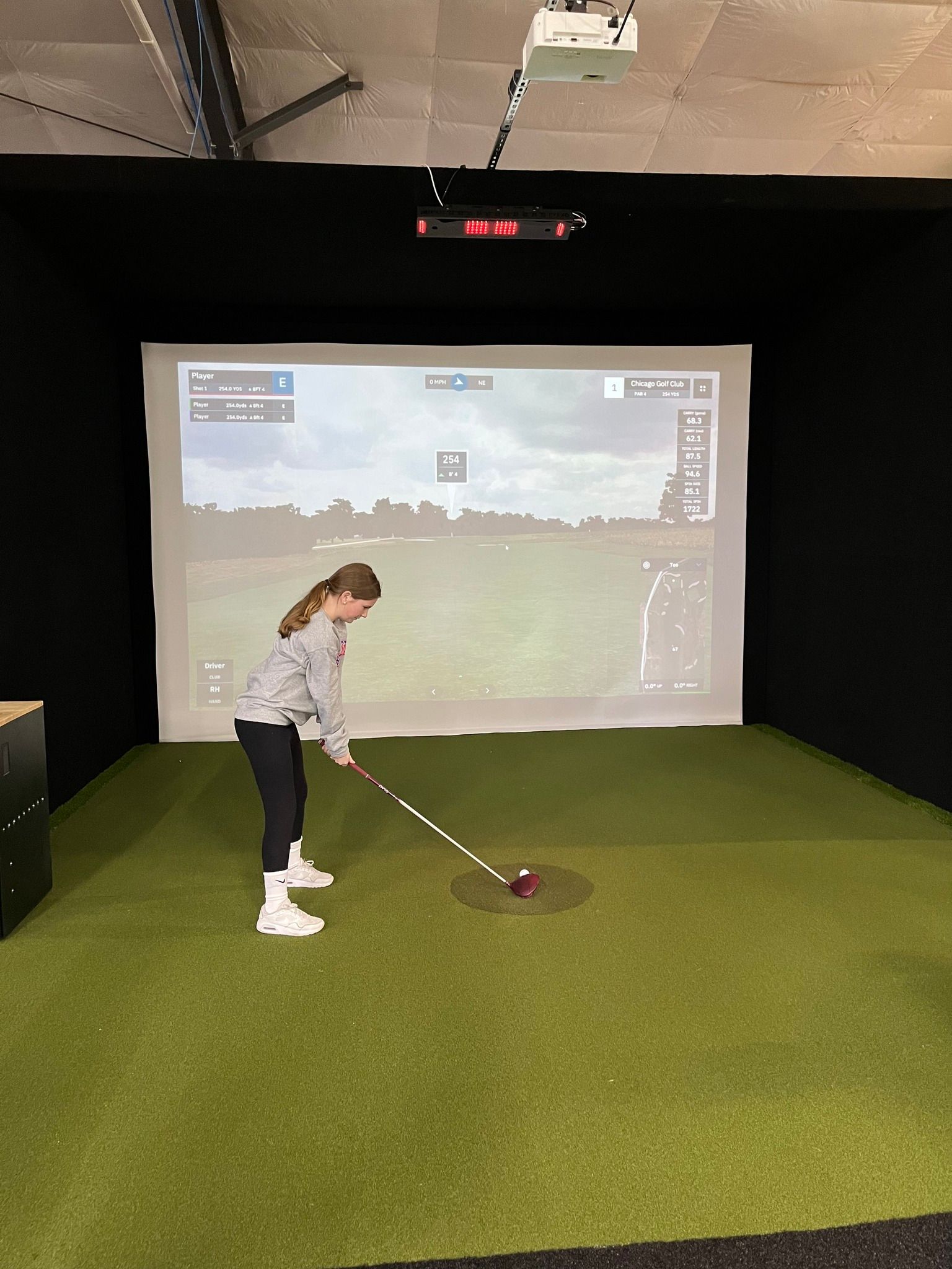 a young girl is playing golf in a simulator .
