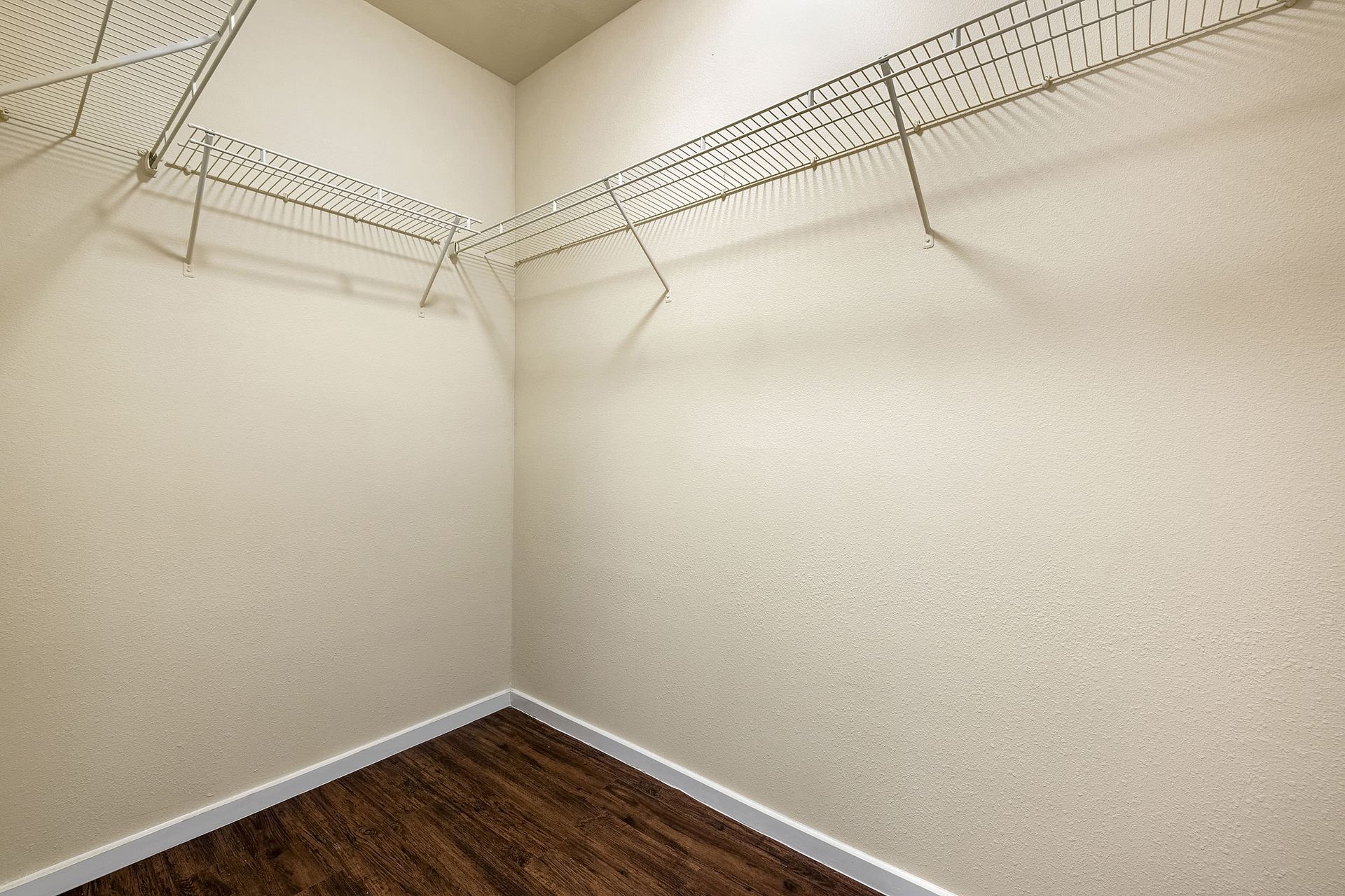 An empty walk in closet with wooden floors and wire shelves at Marquis SoCo in South Austin, TX.