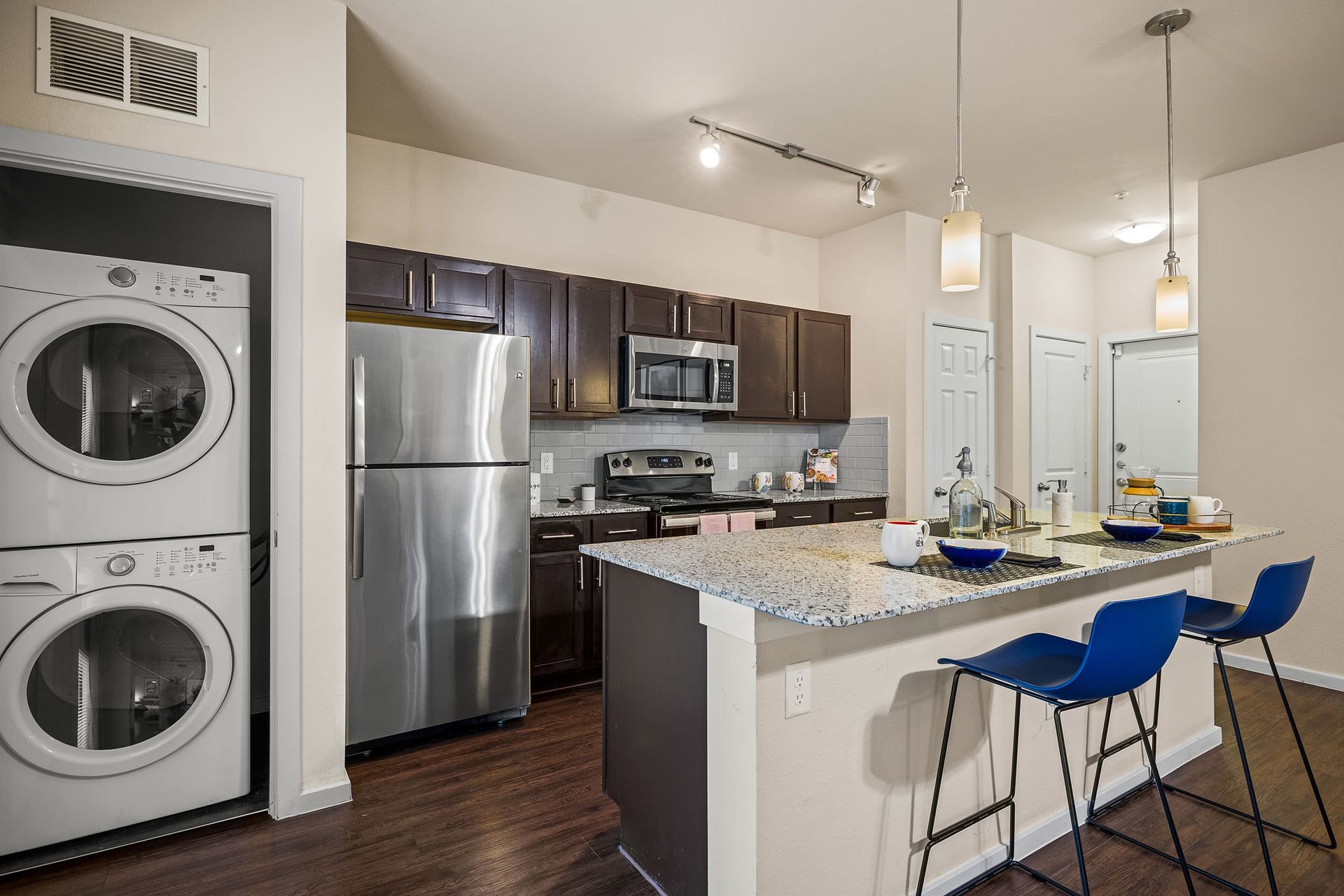 Apartment kitchen with a washer and dryer stacked on top of each other on the side at Marquis SoCo in South Austin, TX.